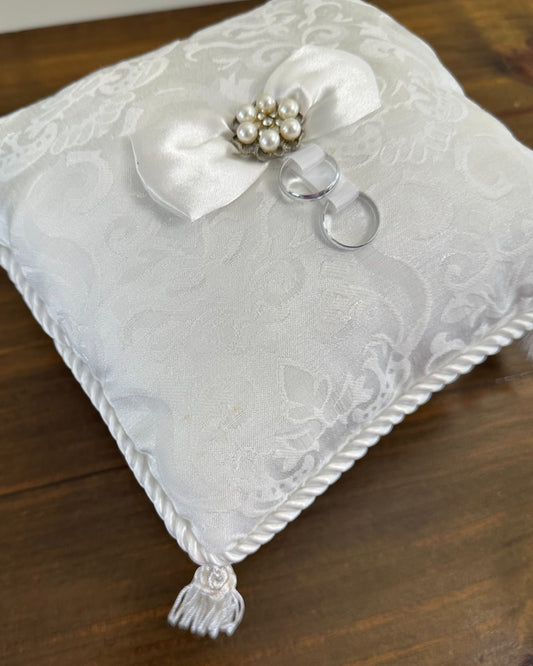 Almofadinha brocado da Etiquette com laço central de pérolas e cristais, fitas para alianças e franjas nas pontas. Modelo clássico e sofisticado.