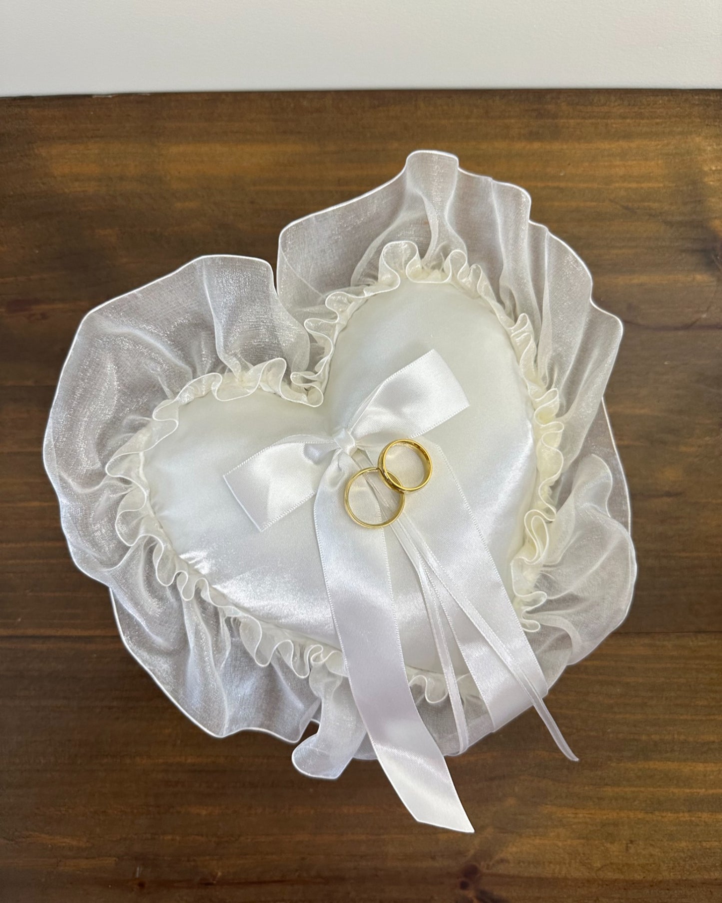Almofadinha para alianças em formato de coração, em cetim offwhite com babado de organza. Modelo romântico da Etiquette.