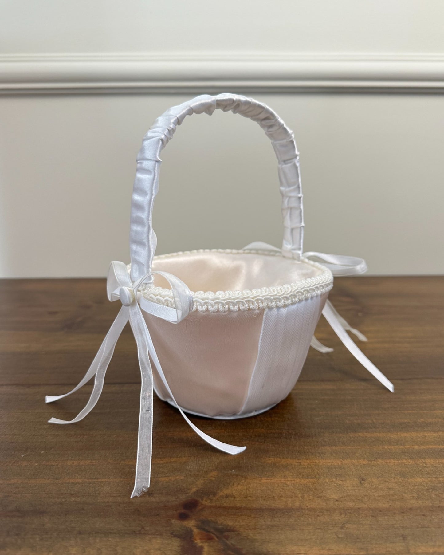 Cestinha da Etiquette em cetim branco com detalhe de fitas nas laterais. Modelo simples e elegante para cerimônias delicadas.
