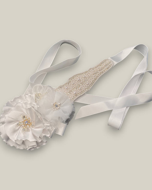 Cinto para noiva com bordado em pérolas e aplicação de flores em tecido branco com miolo em cristais e pérolas sobre faixa de cetim branca.