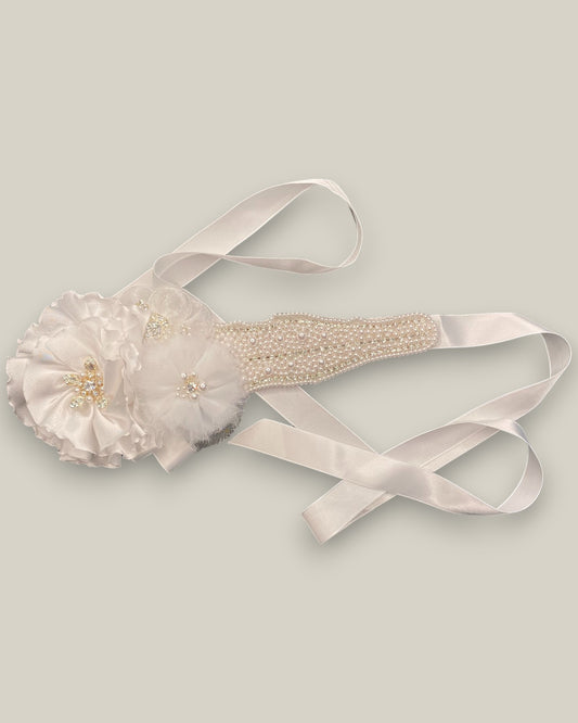 Cinto para noiva com bordado em pérolas e aplicação de flores em tecido branco com miolo em cristais e pérolas sobre faixa de cetim branca.