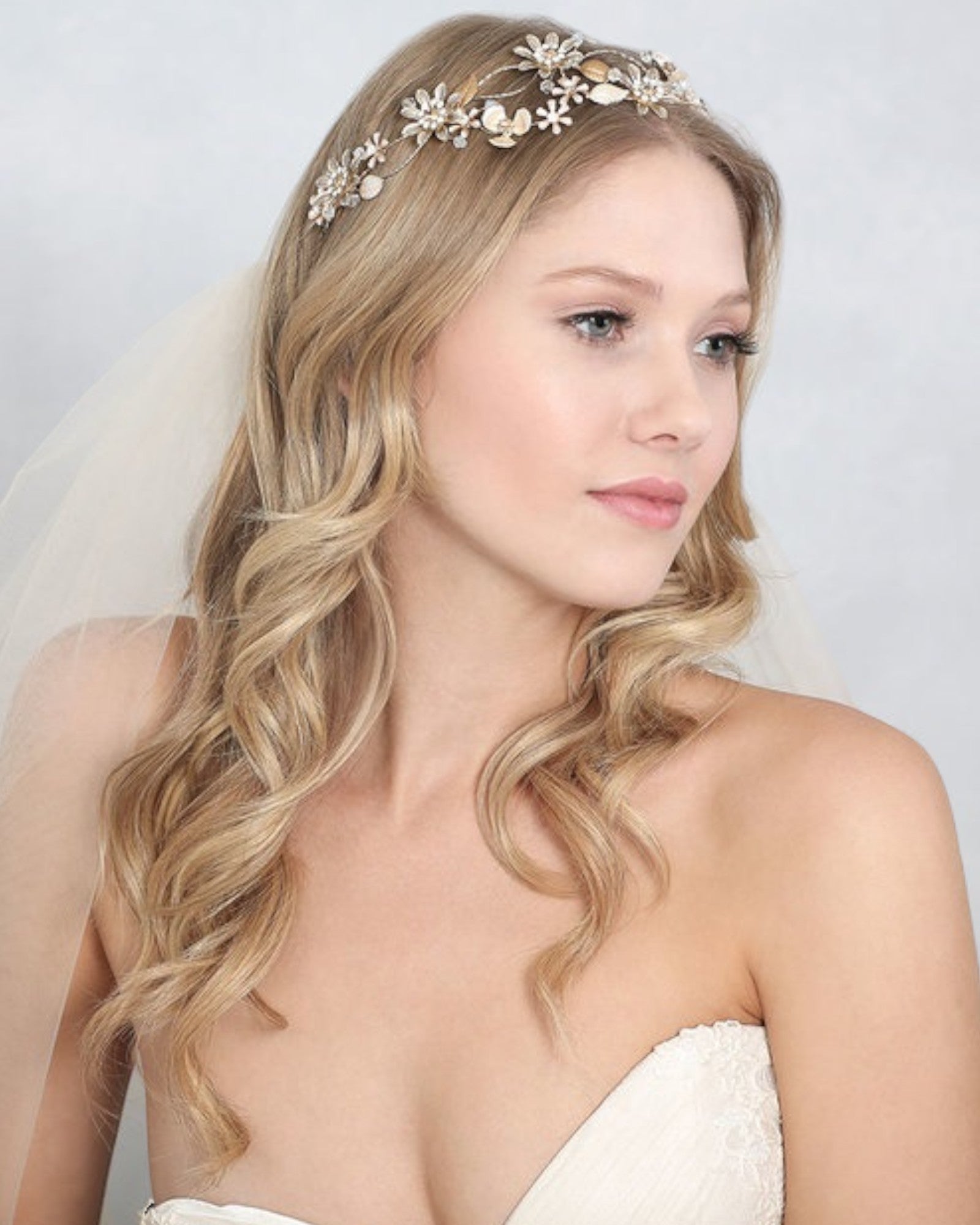 Headband para noivas com flores em metal 3D e detalhes de cristal que explodem ao longo de uma faixa de metal flexível e entrelaçado.