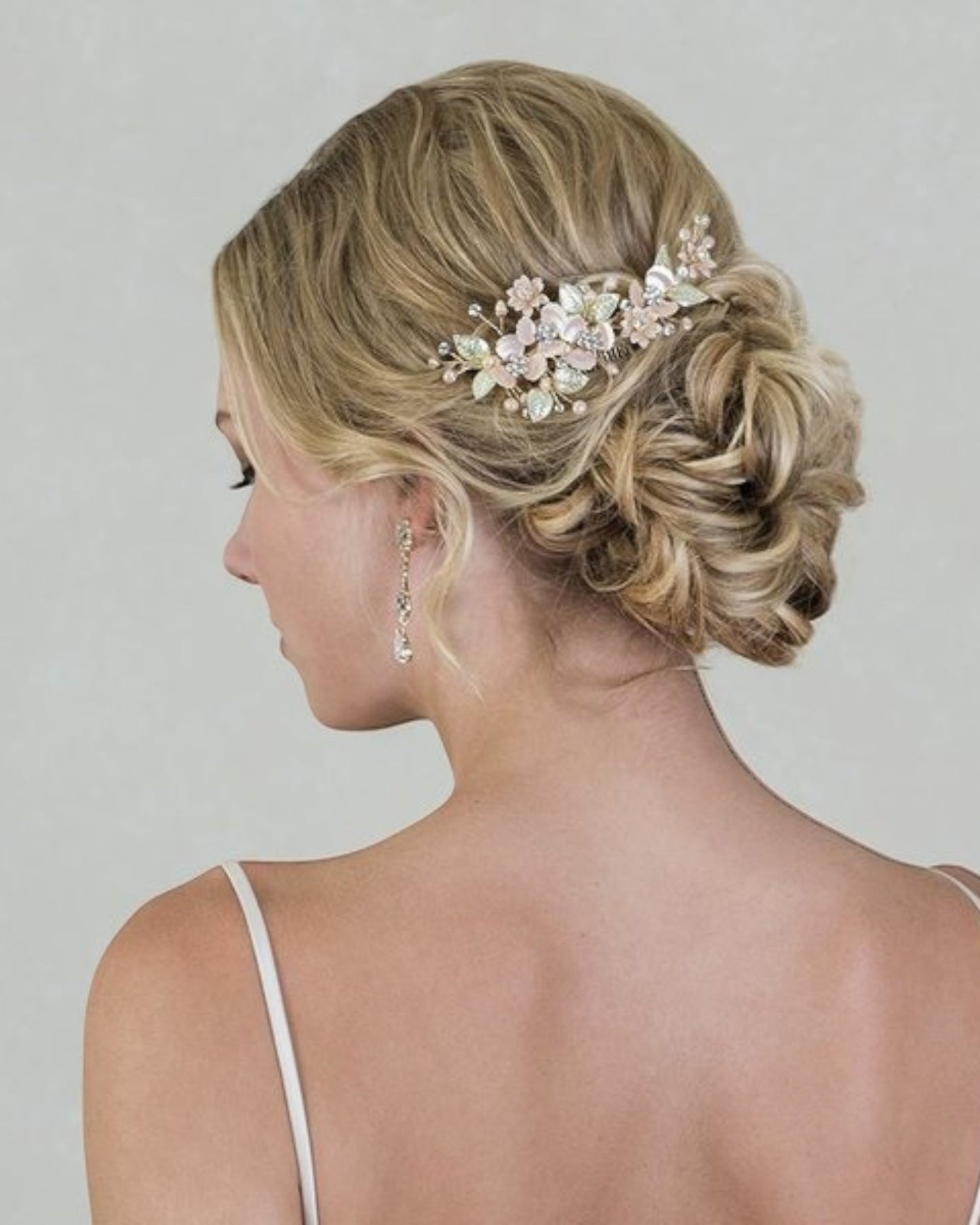Delicado pente em metal banhado em ouro light com aplicação de flores metálicas suavemente pintadas em tons de rosa e verde com detalhes no centro em cristais e pérolas.