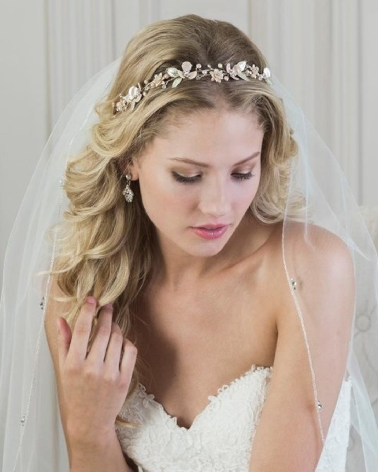 Delicada tiara flexível em metal banhada na cor ouro light com aplicação de flores metálicas suavemente pintadas em tons de rosa e verde com detalhes no centro em cristais e pérolas.