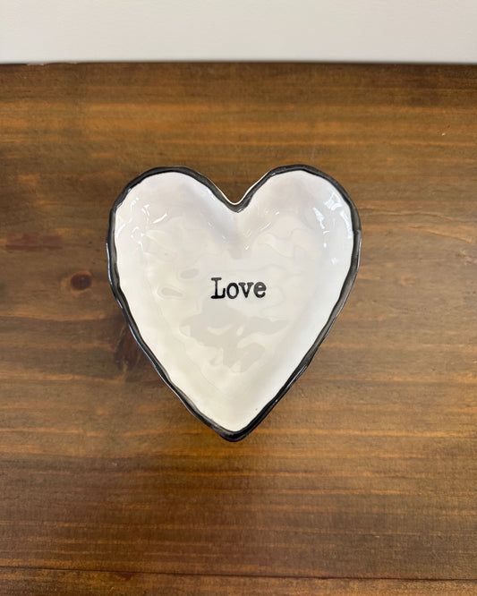Pratinho porta alianças em porcelana em formato de coração com borda preta e palavra “love”. Modelo romântico e moderno da Etiquette.
