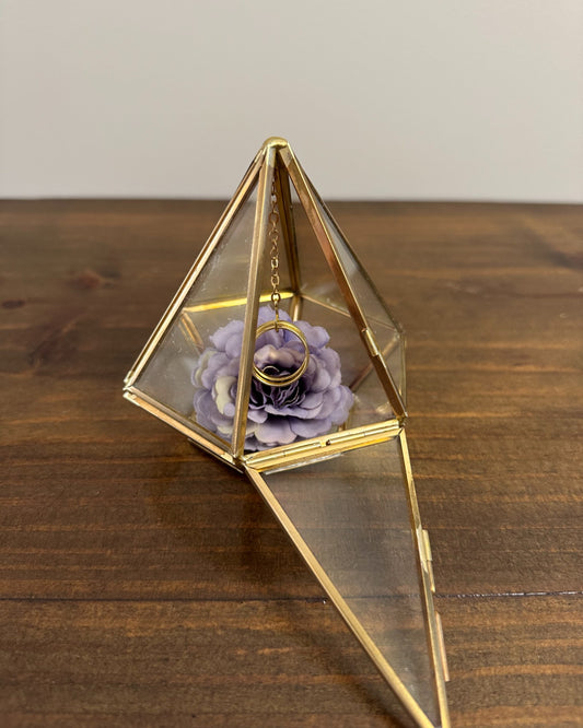 Porta alianças Prisma da Etiquette, em vidro com estrutura dourada, corrente interna e flor decorativa. Moderno, leve e sofisticado.