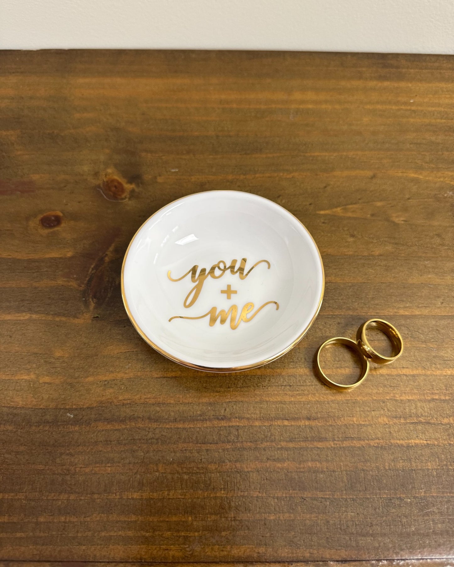 Pratinho porta-alianças da Etiquette em porcelana vitrificada com borda e escrita dourada “You + Me”. Romântico e moderno.