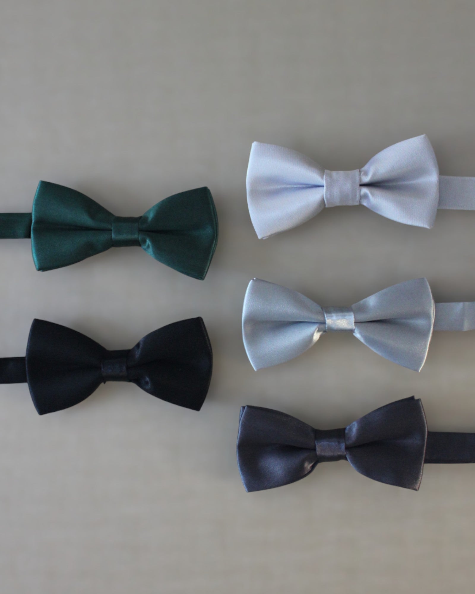 Gravatinha borboleta infantil em cetim nos tons formais — preto, prata e verde musgo — com regulagem no pescoço.