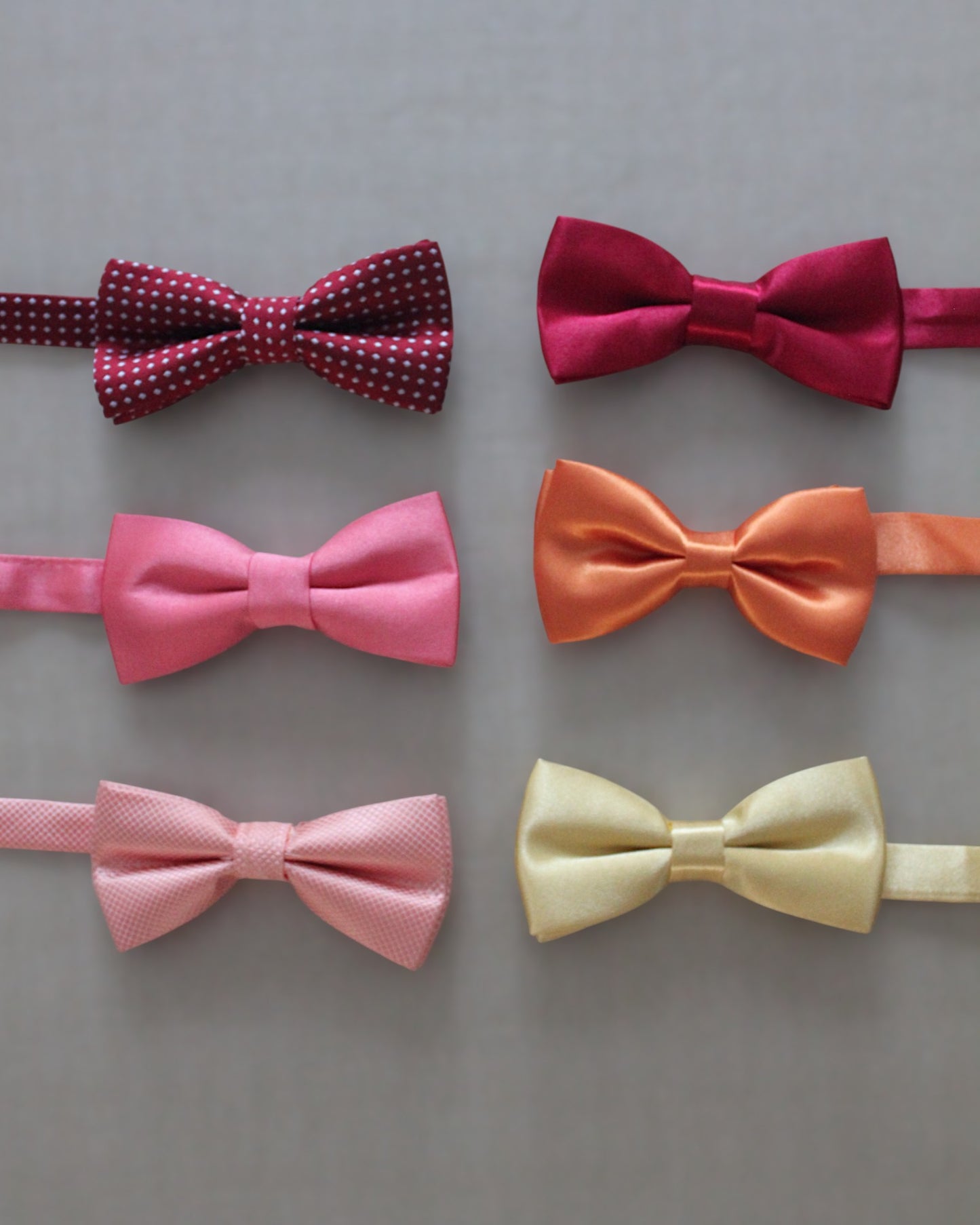 Gravatinha borboleta infantil em cetim nos tons vermelho, coral e amarelo. Acessório regulável para pajens.