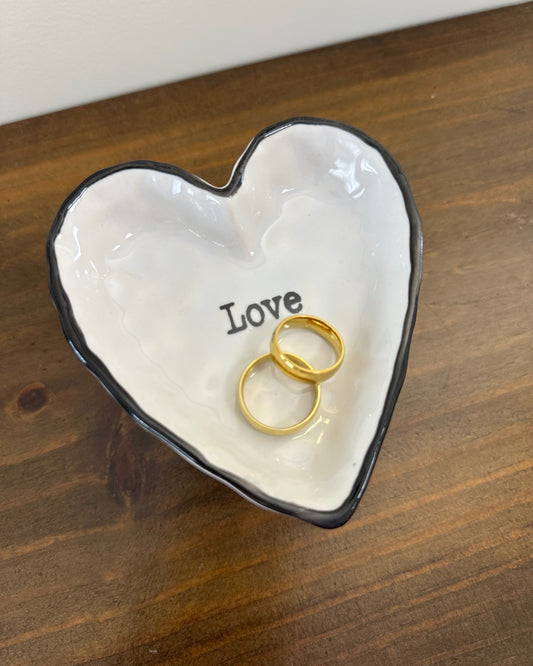 Pratinho porta alianças em porcelana em formato de coração com borda preta e palavra “love”. Modelo romântico e moderno da Etiquette.